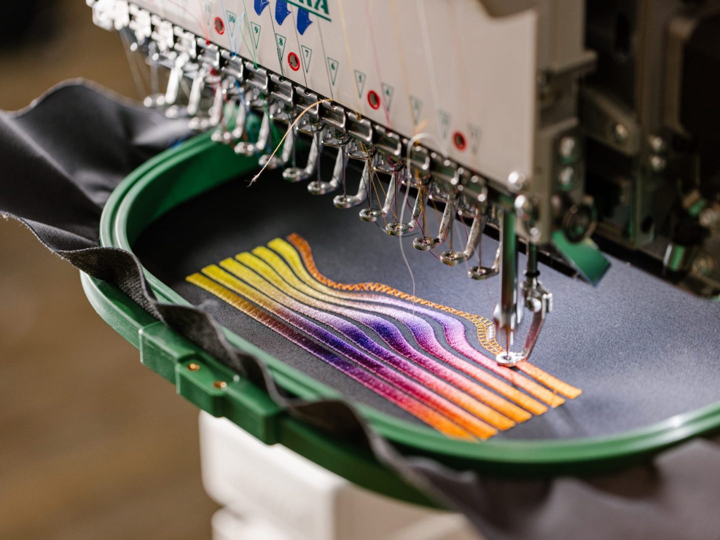 Stickmaschine stickt ein farbiges Motiv auf Stoff